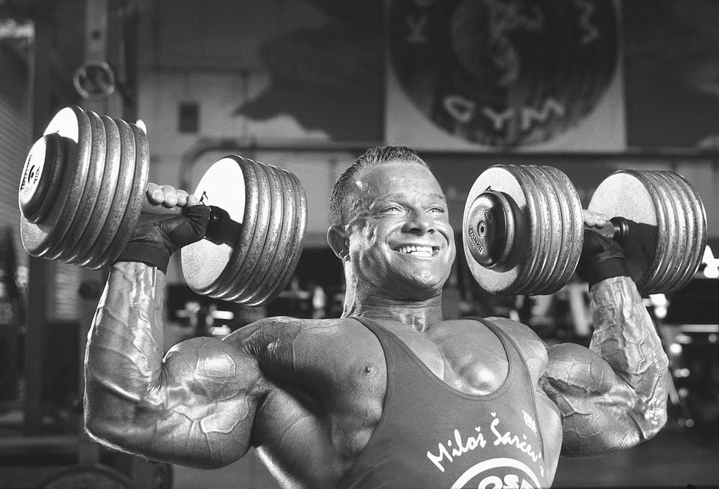 black & white image of the coach while is lifting weights in the gym.